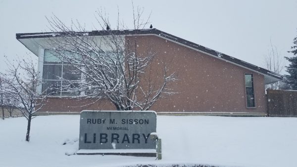 The Ruby M. Sisson Library building and sign, during a snowstorm.