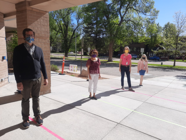 Longmont Public Library Staff stand outside the library, aligned with ground marking indicating safe social distancing. 